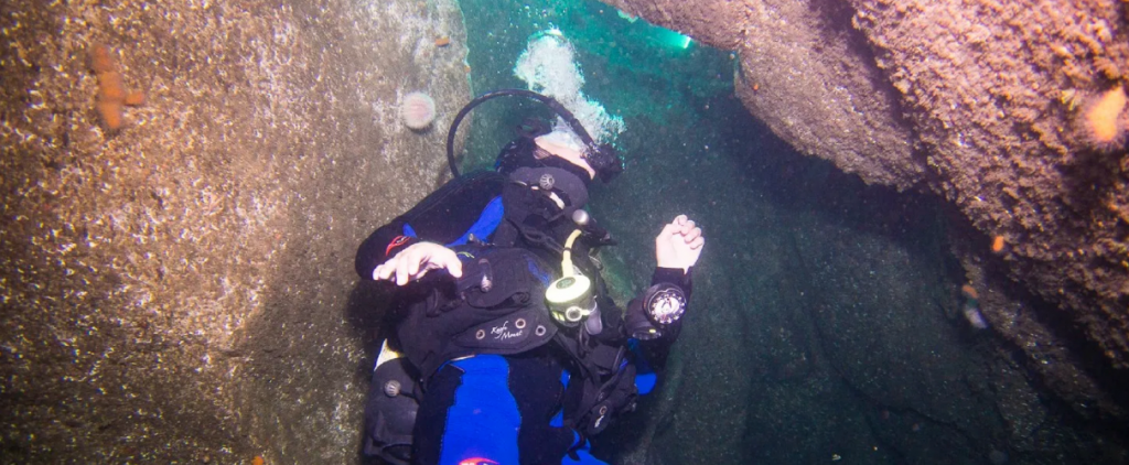 Scuba diver under water between two rocks